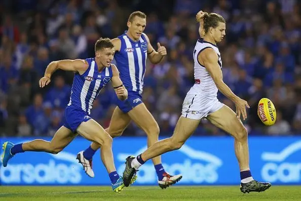 MELBOURNE, AUSTRALIA - APRIL 17: Nat Fyfe of the Dockers kicks the ball for a goal from Ben Jacobs (L) and Drew Petrie of the Kangaroos during the Round 4 AFL match between North Melbourne v Fremantle at Etihad Stadium on April 17, 2016 in Melbourne, Australia. (Photo by Michael Dodge/Getty Images)