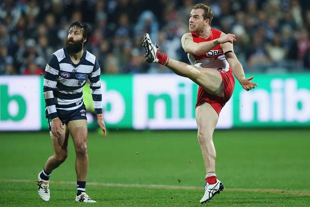 GEELONG, AUSTRALIA - JULY 08: Tom Mitchell of the Swans kicks the ball past Jimmy Bartel of the Cats during the round 16 AFL match between the Geelong Cats and the Sydney Swans at Simonds Stadium on July 8, 2016 in Geelong, Australia. (Photo by Michael Dodge/Getty Images)