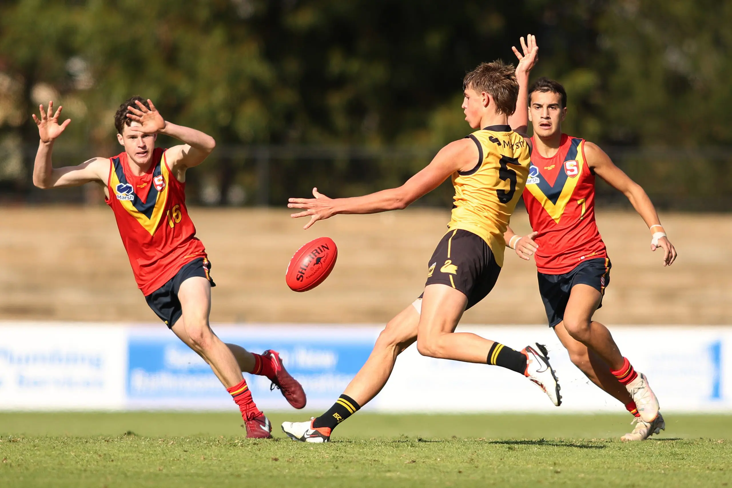 ADELAIDE, AUSTRALIA - JUNE 22: Koby LeCras of Western Australia kicks the ball past William Cameron and Zackariah Young of South Australia during the Marsh AFL National Development Championships match between U16 Boys South Australia and Western Australia at Thebarton Oval on June 22, 2024 in Adelaide, Australia. (Photo by Maya Thompson/AFL Photos/via Getty Images)