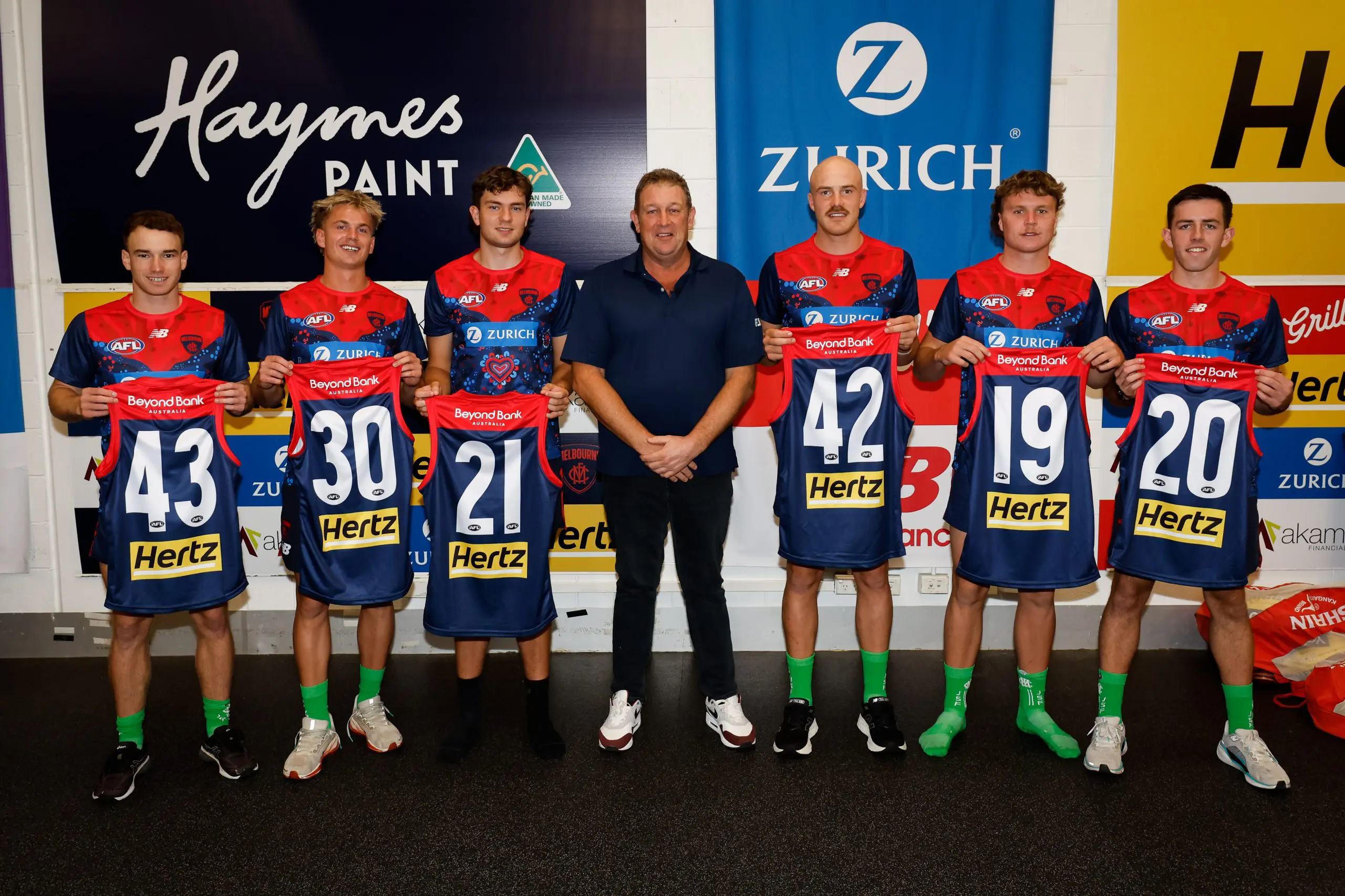 MELBOURNE, AUSTRALIA - MARCH 16: Melbourne Demons debutants Jack Henderson, Harry Sharp, Matthew Jefferson, Aidan Johnson, Harvey Langford and Xavier Lindsay pose for a photo with former player David Schwarz before the 2025 AFL Round 01 match between the Melbourne Demons and the GWS Giants at the Melbourne Cricket Ground on March 16, 2025 in Melbourne, Australia. (Photo by Dylan Burns/AFL Photos via Getty Images)