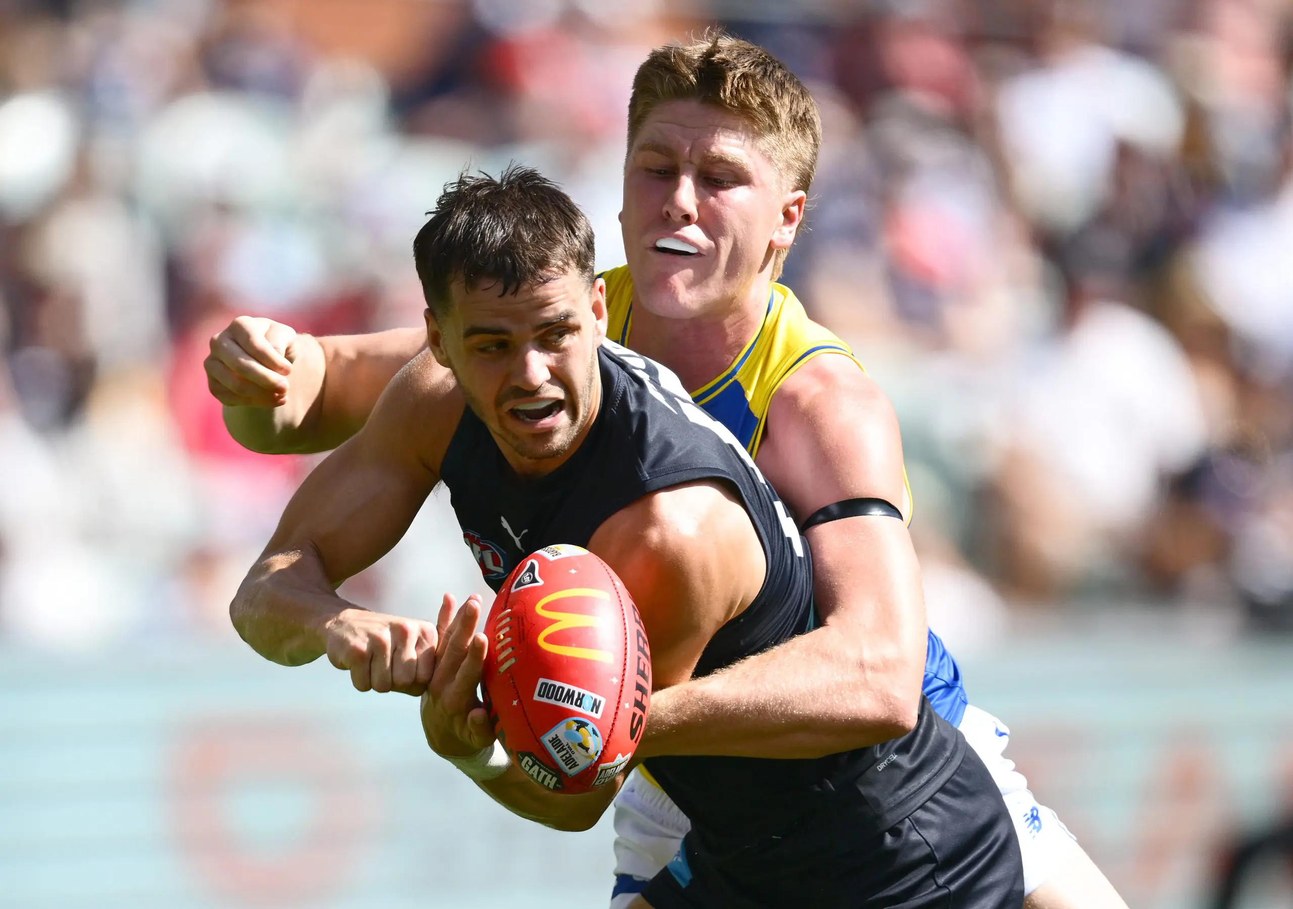 ADELAIDE, AUSTRALIA - APRIL 12: Brodie Kemp of the Blues handballs whilst being tackled during the round five AFL match between Carlton Blues and West Coast Eagles at Adelaide Oval, on April 12, 2025, in Adelaide, Australia. (Photo by Quinn Rooney/Getty Images)