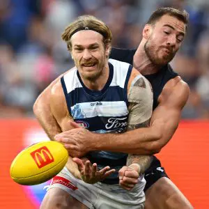 MELBOURNE, AUSTRALIA - APRIL 27: Tom Stewart of the Cats handballs whilst being tackled by Harry McKay of the Blues during the round seven AFL match between Carlton Blues and Geelong Cats at Melbourne Cricket Ground, on April 27, 2025, in Melbourne, Australia. (Photo by Quinn Rooney/Getty Images)
