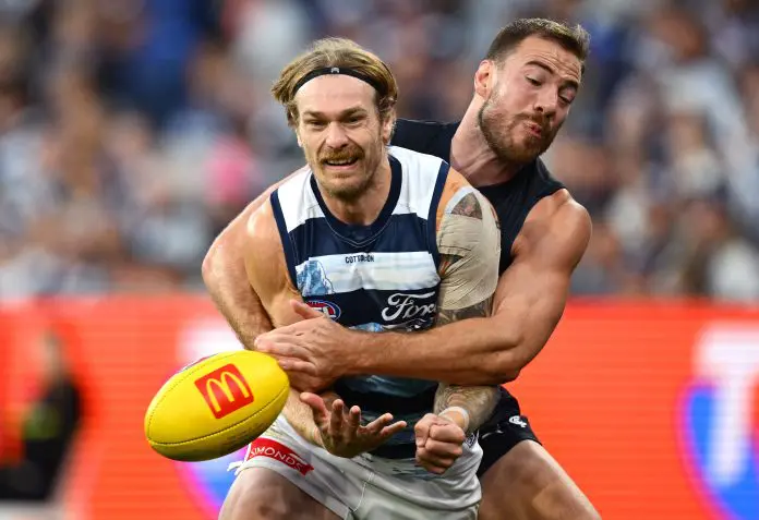 MELBOURNE, AUSTRALIA - APRIL 27: Tom Stewart of the Cats handballs whilst being tackled by Harry McKay of the Blues during the round seven AFL match between Carlton Blues and Geelong Cats at Melbourne Cricket Ground, on April 27, 2025, in Melbourne, Australia. (Photo by Quinn Rooney/Getty Images)