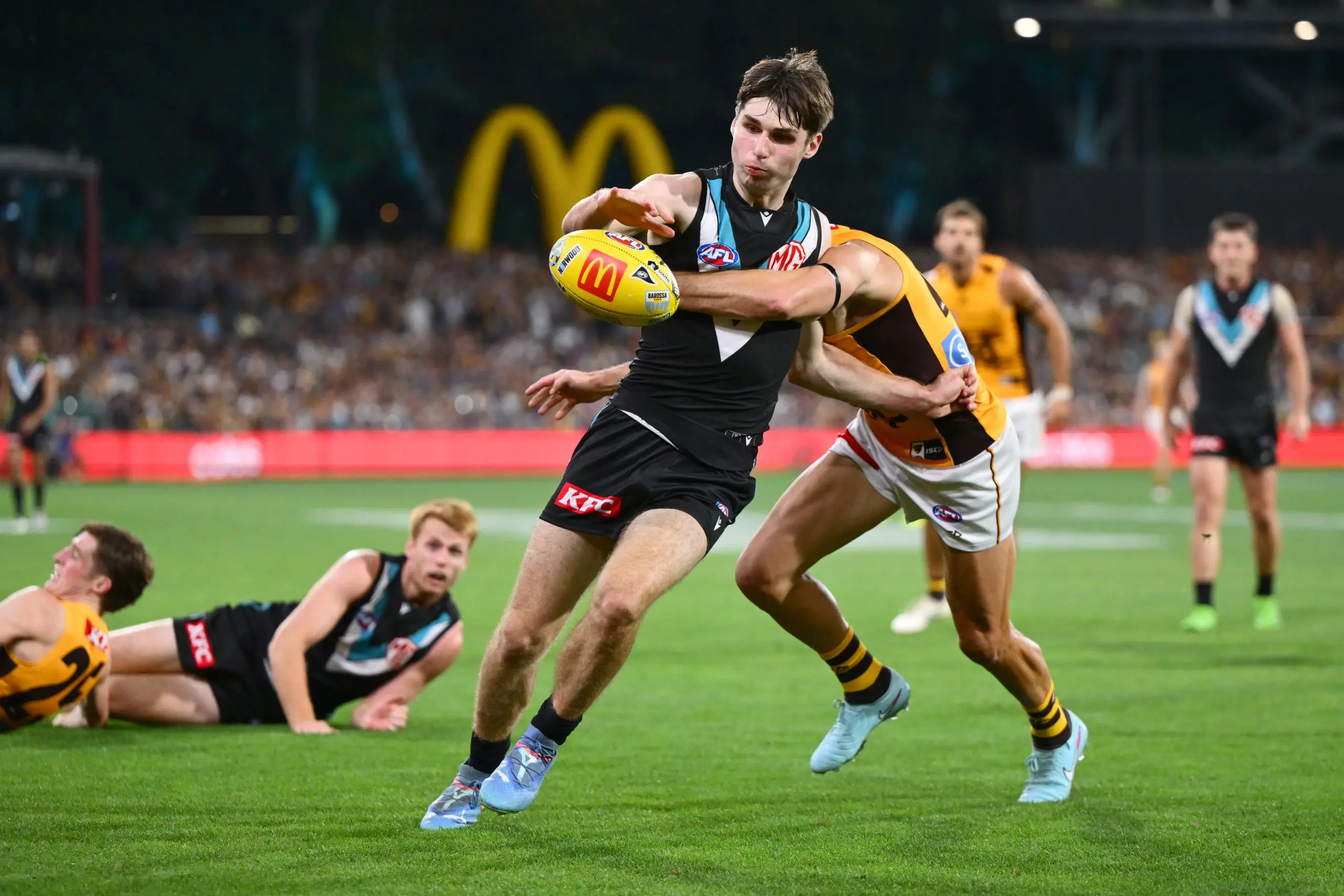 ADELAIDE, AUSTRALIA - APRIL 13: Christian Moraes of the Power kicks the ball while being tackled during the round five AFL match between Port Adelaide Power and Hawthorn Hawks at Adelaide Oval, on April 13, 2025, in Adelaide, Australia. (Photo by Quinn Rooney/Getty Images)
