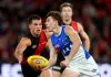 MELBOURNE, AUSTRALIA - MAY 01: Finn O'Sullivan of the Kangaroos handballs whilst being tackled by esapduring the round eight AFL match between Essendon Bombers and North Melbourne Kangaroos at Marvel Stadium, on May 01, 2025, in Melbourne, Australia. (Photo by Josh Chadwick/Getty Images)