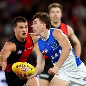 MELBOURNE, AUSTRALIA - MAY 01: Finn O'Sullivan of the Kangaroos handballs whilst being tackled by esapduring the round eight AFL match between Essendon Bombers and North Melbourne Kangaroos at Marvel Stadium, on May 01, 2025, in Melbourne, Australia. (Photo by Josh Chadwick/Getty Images)