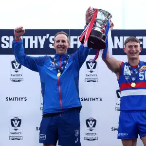 MELBOURNE, AUSTRALIA - SEPTEMBER 21: Stewart Edge, Senior Coach of the Bulldogs and Daniel Orgill of the Bulldogs hold the premiership cup aloft after winning the VFL Grand Final match between Footscray Bulldogs and Southport Sharks at Ikon Park on September 21, 2025 in Melbourne, Australia. (Photo by Josh Chadwick/AFL Photos/via Getty Images)
