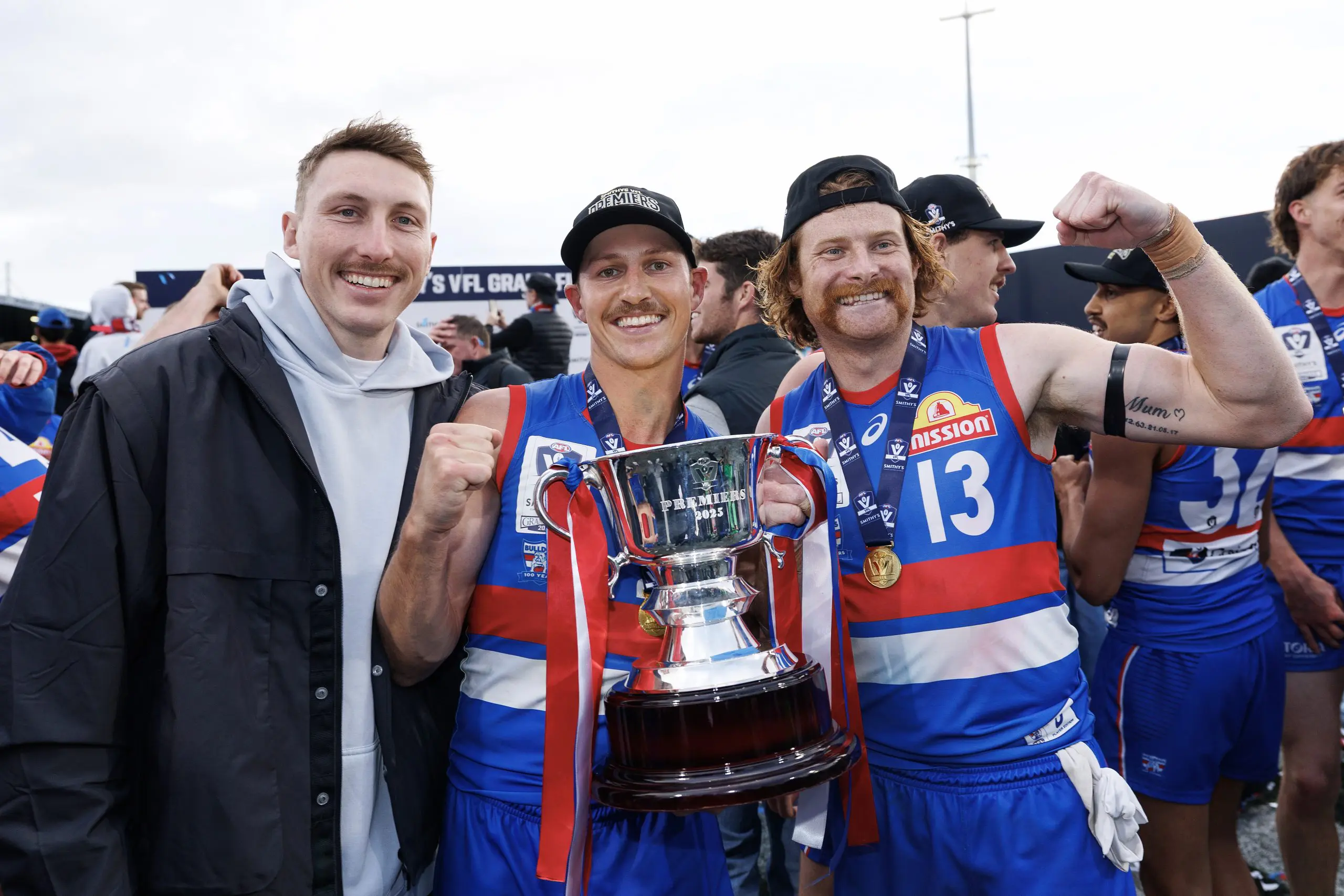MELBOURNE, AUSTRALIA - SEPTEMBER 21: Anthony Scott of the Bulldogs and Oskar Baker of the Bulldogs pose with Bailey Dale of the Bulldogs and the trophy during the 2025 VFL Grand Final match between Footscray Bulldogs and Southport Sharks at Ikon Park on September 21, 2025 in Melbourne, Australia. (Photo by Daniel Pockett/Getty Images)
