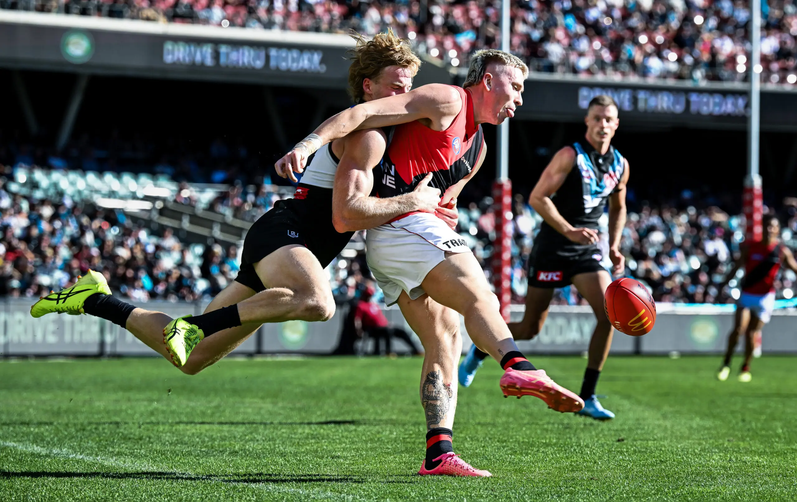 ADELAIDE, AUSTRALIA - MARCH 22: Nate Caddy of the Bombers tackled by Miles Bergman of the Power during the round two AFL match between Port Adelaide Power and Essendon Bombers at Adelaide Oval, on March 22, 2026, in Adelaide, Australia. (Photo by Mark Brake/Getty Images)