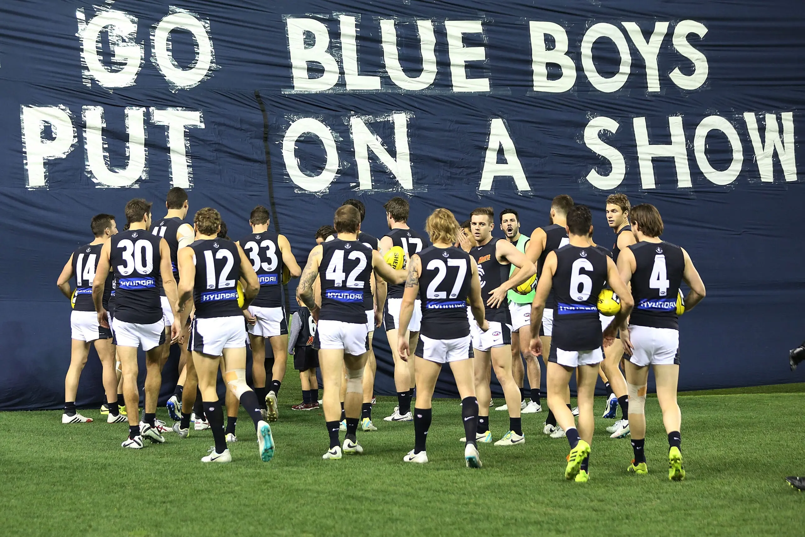MELBOURNE, AUSTRALIA - JUNE 06: Blues players walk up to the banner during the round 12 AFL match between the Geelong Cats and the Carlton Blues at Etihad Stadium on June 6, 2014 in Melbourne, Australia. (Photo by Michael Dodge/Getty Images)