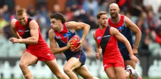 FINAL TEAMS: Melbourne vs Essendon – Round 14, 2026 ADELAIDE, AUSTRALIA - APRIL 11: Caleb Windsor of the Demons clears the ball from the centre during the round five AFL match between Essendon Bombers and Melbourne Demons at Adelaide Oval, on April 11, 2026, in Adelaide, Australia. (Photo by Quinn Rooney/Getty Images)