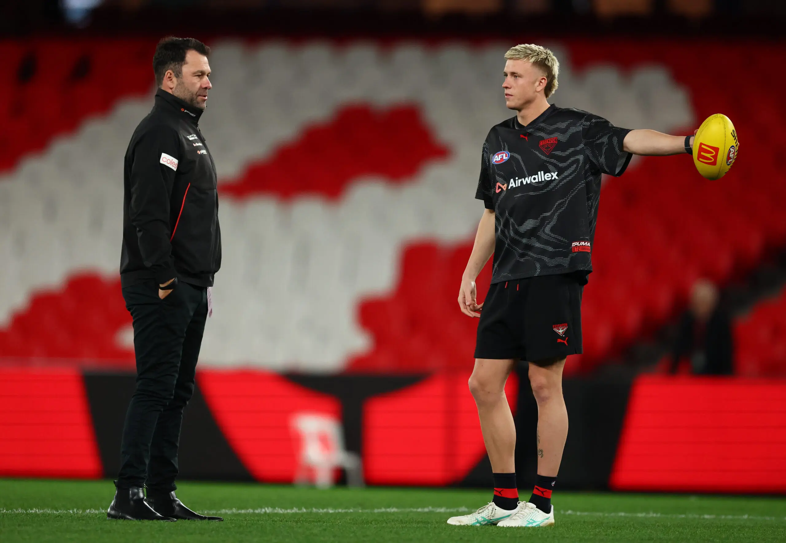 MELBOURNE, AUSTRALIA - AUGUST 02: Bombers interim senior coach, Dean Solomon speaks Nate Caddy prior to the round 21 AFL match between Essendon Bombers and Adelaide Crows at Marvel Stadium, on August 02, 2026, in Melbourne, Australia. (Photo by Robert Cianflone/Getty Images)