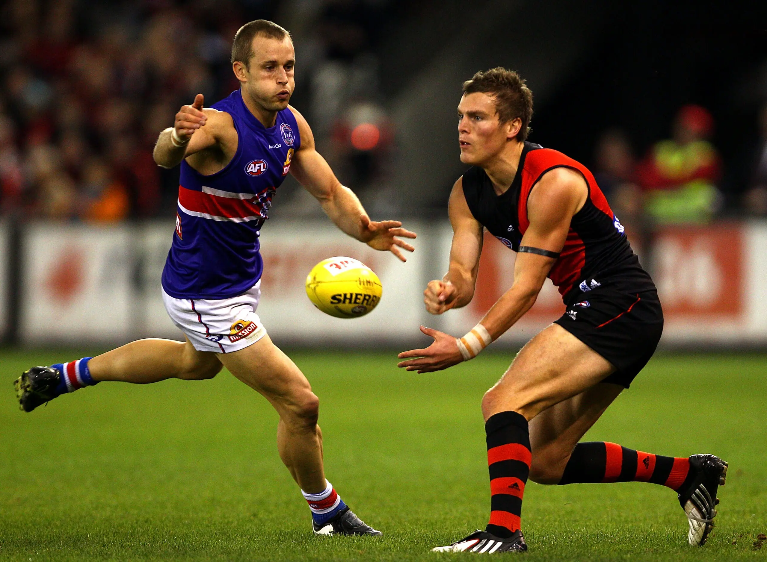 MELBOURNE, AUSTRALIA - MAY 28: Brent Prismall of the Bombers handballs under pressure from Daniel Cross of the Bulldogs during the round 10 AFL match between the Essendon Bombers and the Western Bulldogs at Etihad Stadium on May 28, 2010 in Melbourne, Australia. (Photo by Mark Dadswell/Getty Images)