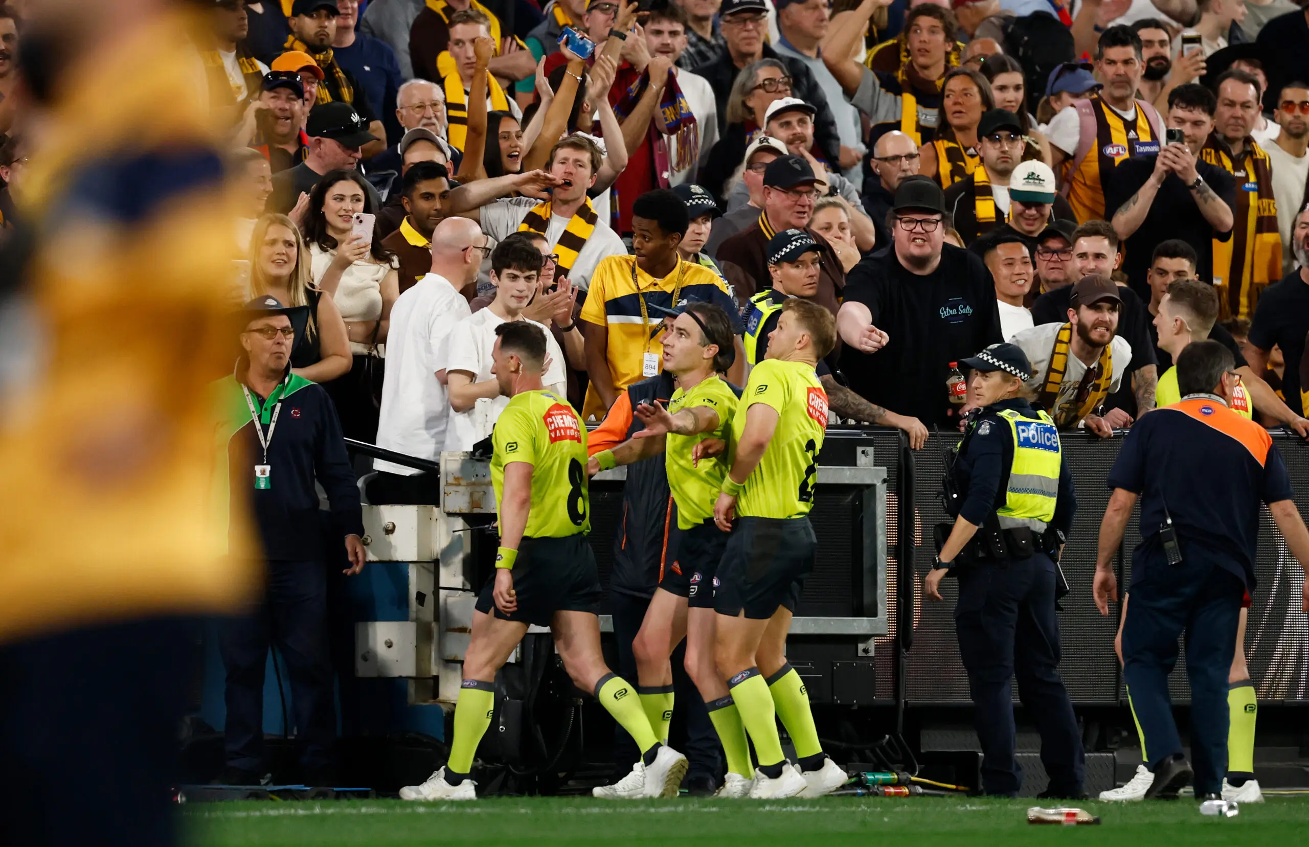 MELBOURNE, AUSTRALIA - SEPTEMBER 19: Umpires dodge bottles thrown by patrons as they leave the field during the 2026 AFL First Preliminary Final between the Hawthorn Hawks and the Brisbane Lions at the Melbourne Cricket Ground on September 19, 2026 in Melbourne, Australia. (Photo by Michael Willson/AFL Photos via Getty Images)