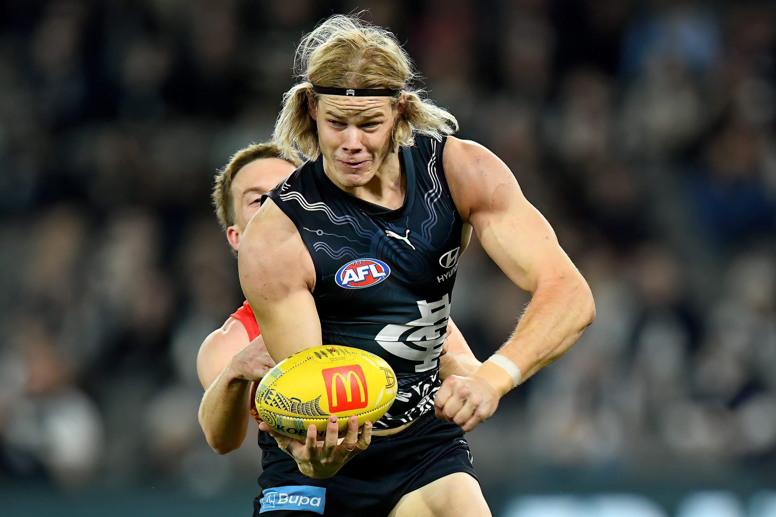 MELBOURNE, AUSTRALIA - MAY 25: Tom De Koning of the Blues handballs whilst being tackled by Noah Anderson of the Suns during the round 11 AFL match between Carlton Blues and Gold Coast Suns at Marvel Stadium, on May 25, 2024, in Melbourne, Australia. (Photo by Josh Chadwick/AFL Photos/via Getty Images)
