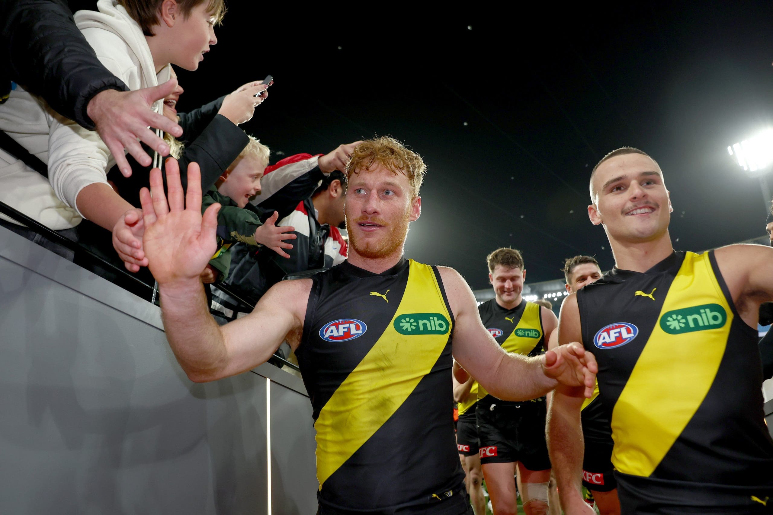 MELBOURNE, AUSTRALIA - JULY 12: Nick Vlastuin of the Tigers and Taj Hotton of the Tigers high fives fans after winning the round 18 AFL match between Richmond Tigers and Essendon Bombers at Melbourne Cricket Ground on July 12, 2025 in Melbourne, Australia. (Photo by Josh Chadwick/AFL Photos/via Getty Images)